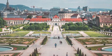 Huge building in Vienna with people walking in the grounds.