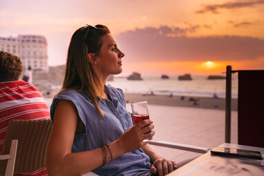 Girl having a drink watching the sunset