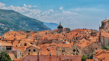 Top of houses in Dubrovnik with mountains in background.