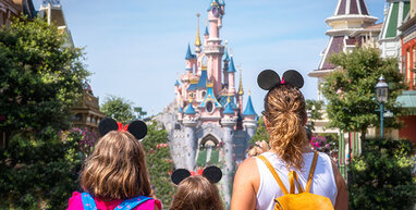 Disneyland Castle behind mum and 2 children.