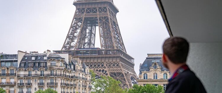 Close up of the bottom of the Eiffel Tower with the back of a man looking.