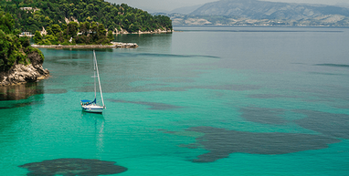 Boat sailing about Corfu on a green clear sea.