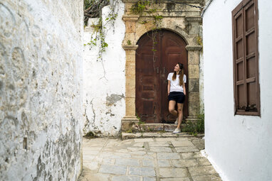 Girl leaning against big door in Lindos street