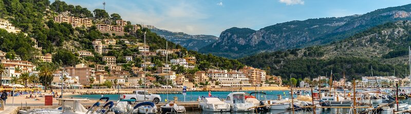 Mallorca bay with boats and mountains with hills in background.