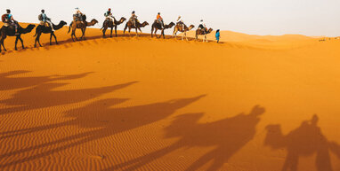 People riding camels across the Marrakech desert.