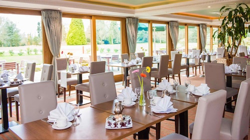 Shendish Manor Hotel - bright dining area with wooden tables set for eating and comfy, cream, leather chairs. Views overlooking the garden.