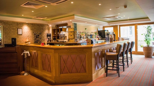 Shendish Manor Hotel - wooden bar area with brown, leather bar stools and an extensive drinks menu.