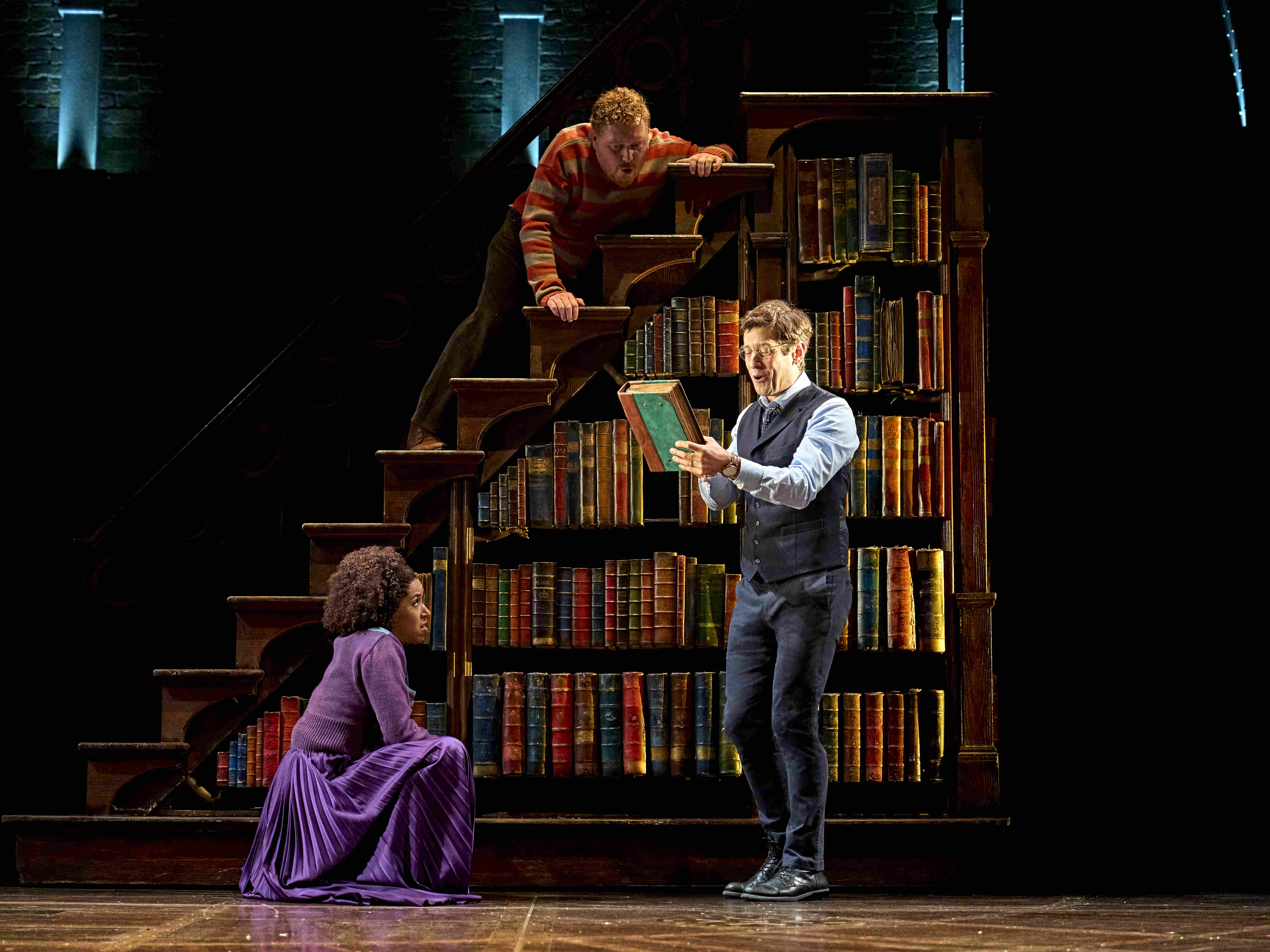 Characters surrounded by floating papers and a magical book with a glowing object, from Harry Potter and the Cursed Child.