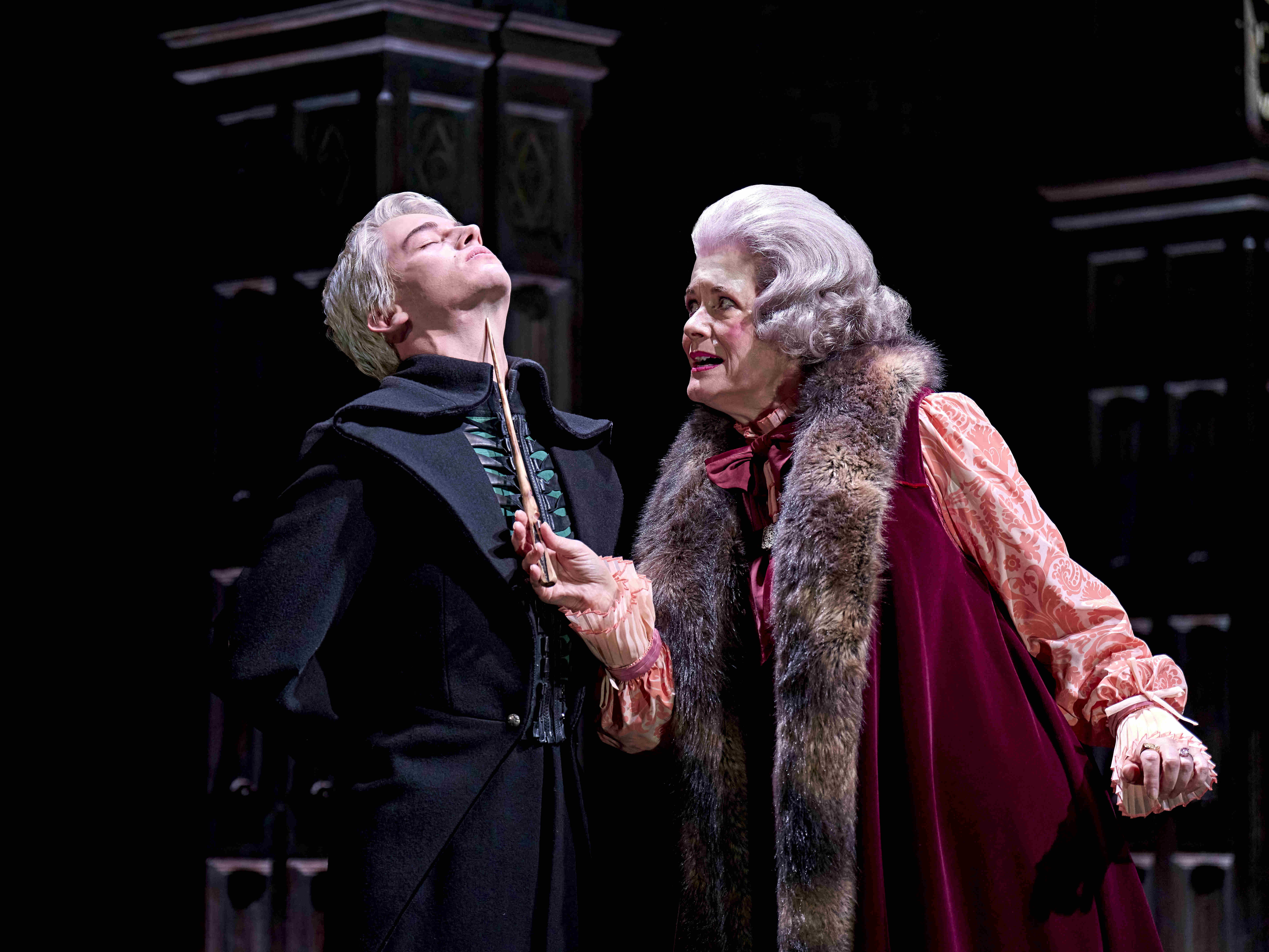 Two characters, Ginny and Harry Potter, smiling at each other while pushing a pram, from Harry Potter and the Cursed Child.