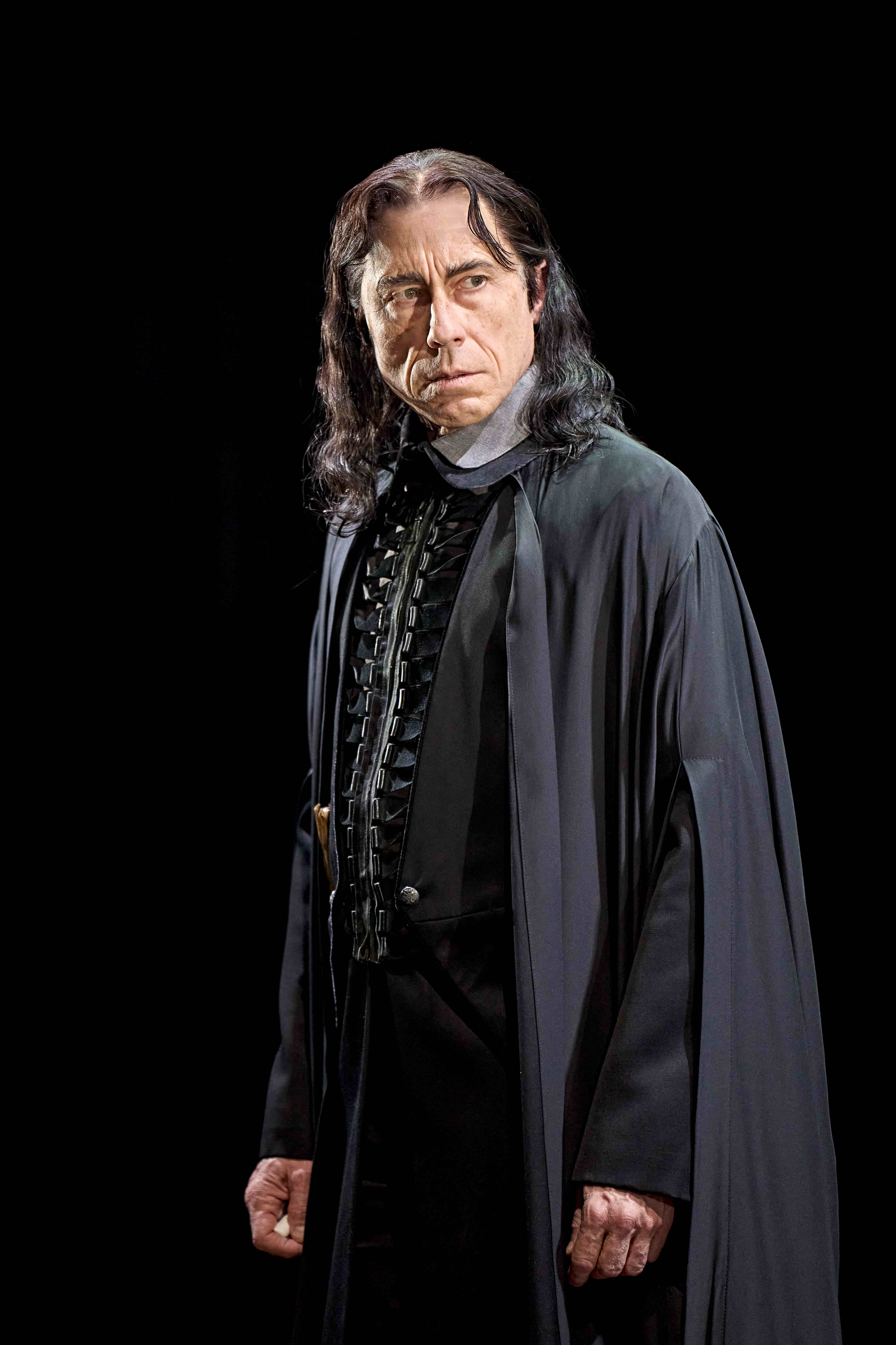 Character standing under a large clock, looking up at a flying hat, from Harry Potter and the Cursed Child.