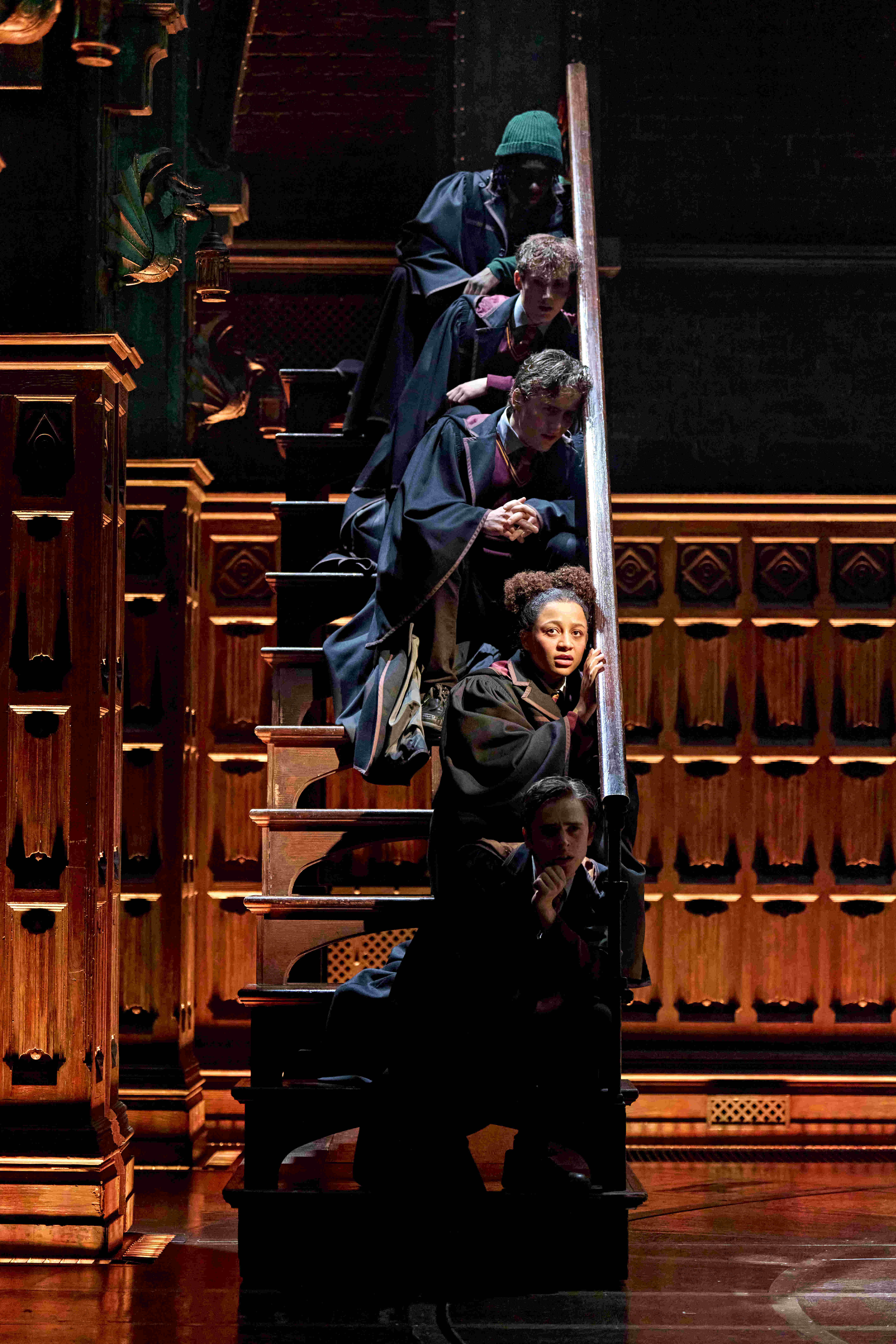 Character standing under a large clock, looking up at a flying hat, from Harry Potter and the Cursed Child.