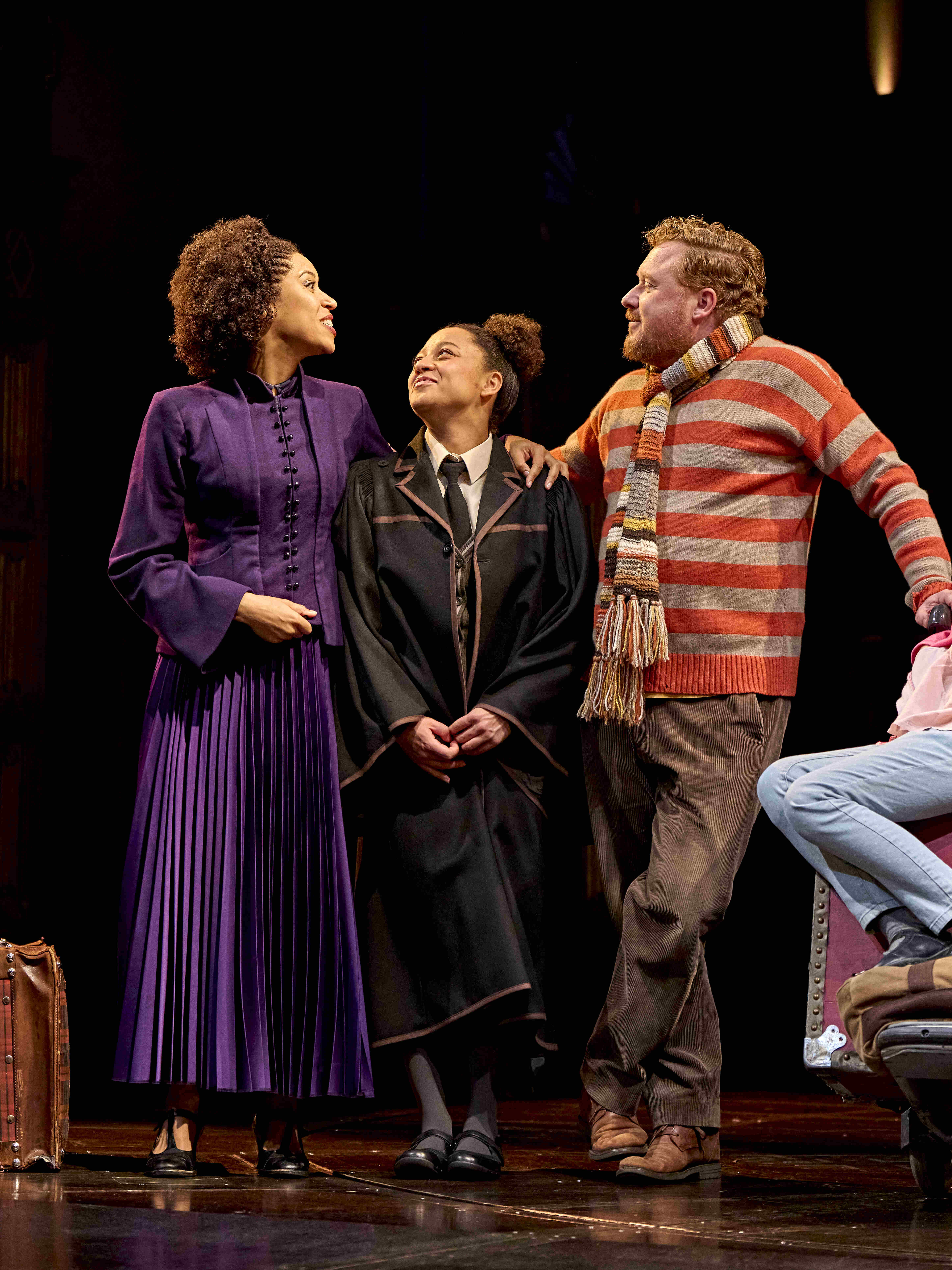 Character with curly hair confidently leading a group of students on stage in Harry Potter and the Cursed Child.
