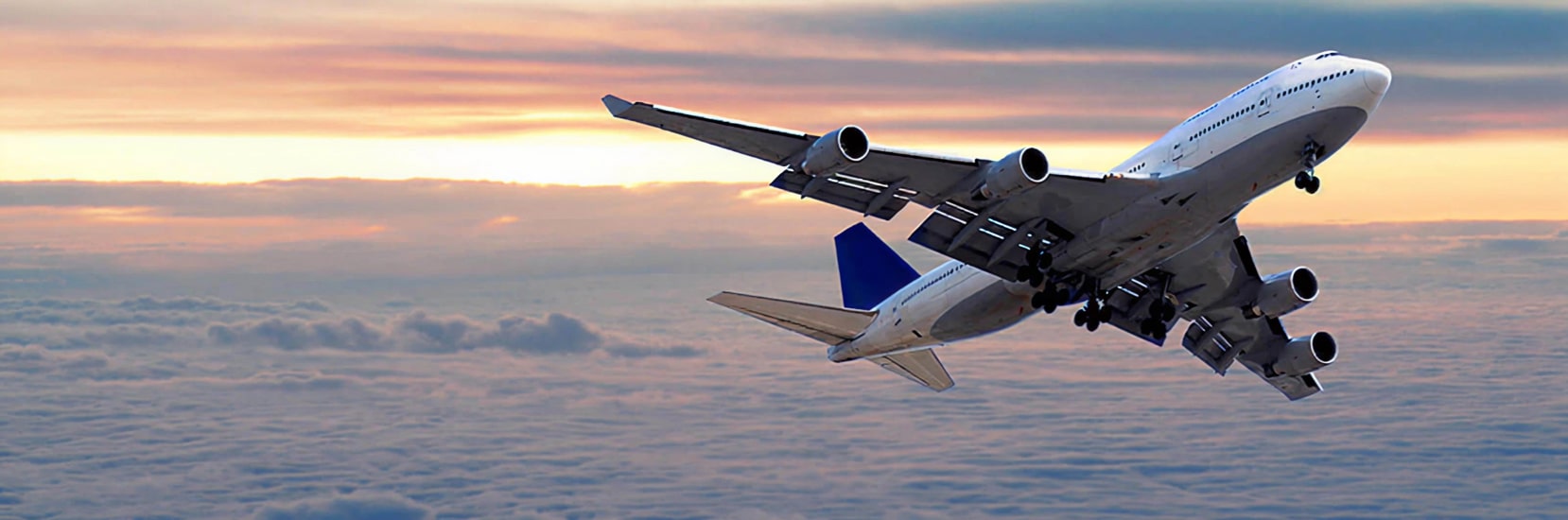 plane in the sky flying over a sunset