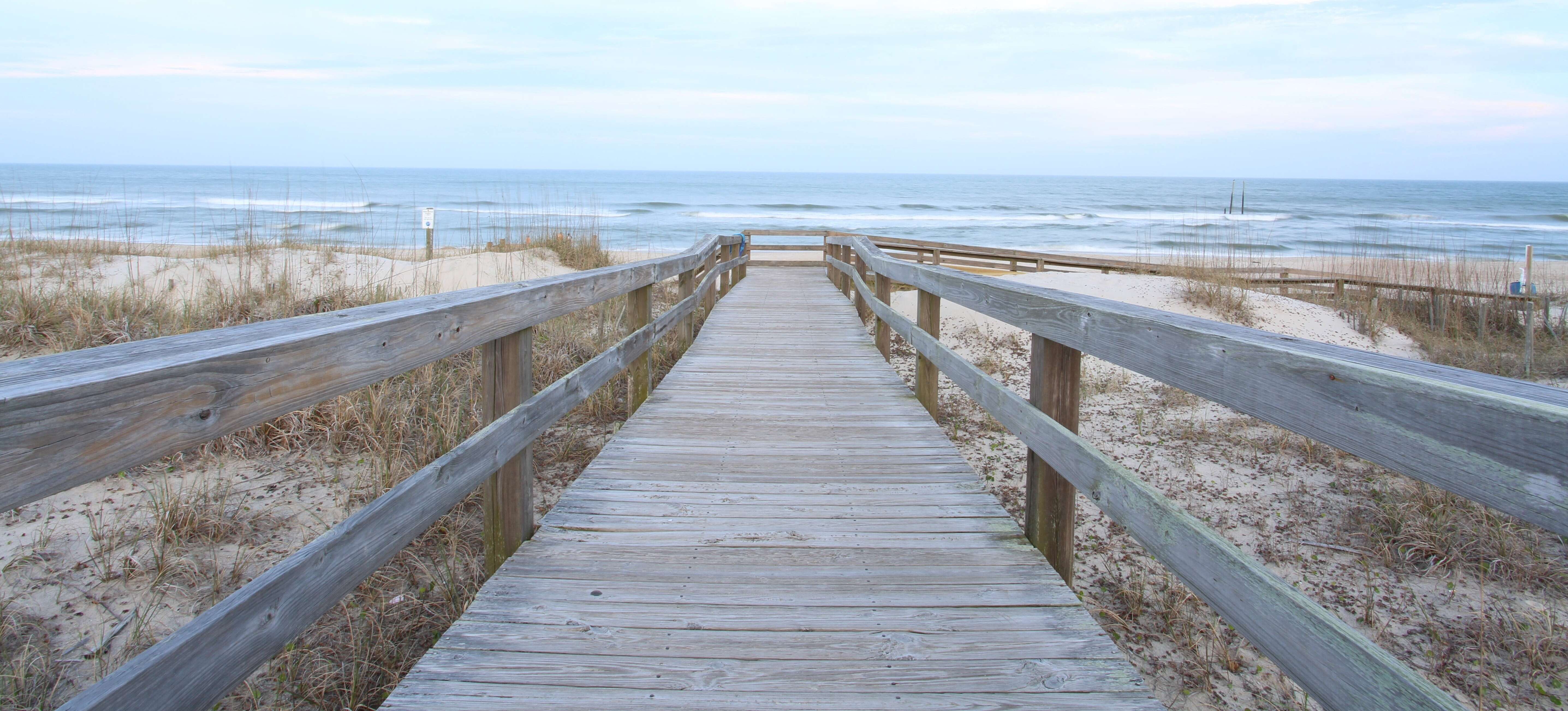 Wooden walkway leading down to the sea along a sandy beach