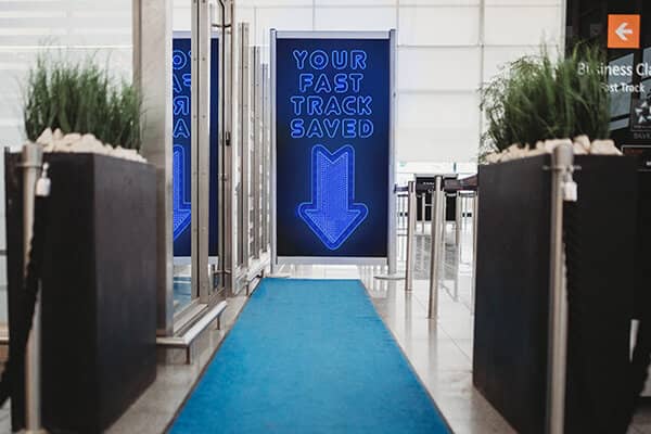 Airport security barrier with neon sign showing fast track walkway