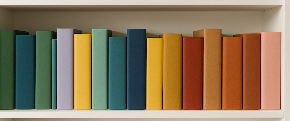 A close-up of a white bookshelf filled with thick, unbranded books in various solid colours arranged neatly side by side.