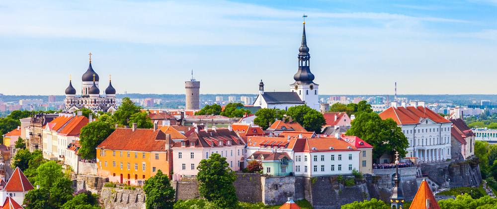 Panoramic view of Tallinn Old Town with red-roofed buildings, Alexander Nevsky Cathedral, St. Mary's Cathedral, and medieval stone towers – historic European cityscape.