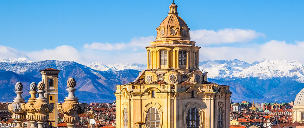Historic domed building overlooking Turin cityscape with snow-capped Alps in the background – iconic European architecture and scenic mountain skyline.