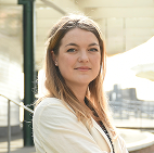 Sophie Haydock, award-winning author, standing confidently outside a modern building in natural sunlight.