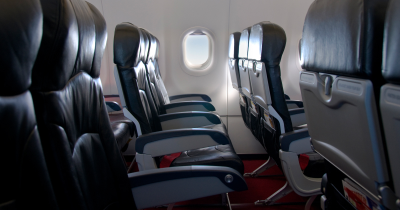 Empty airplane seats in economy class with window views and soft lighting — quiet cabin interior ready for boarding or in-flight travel.