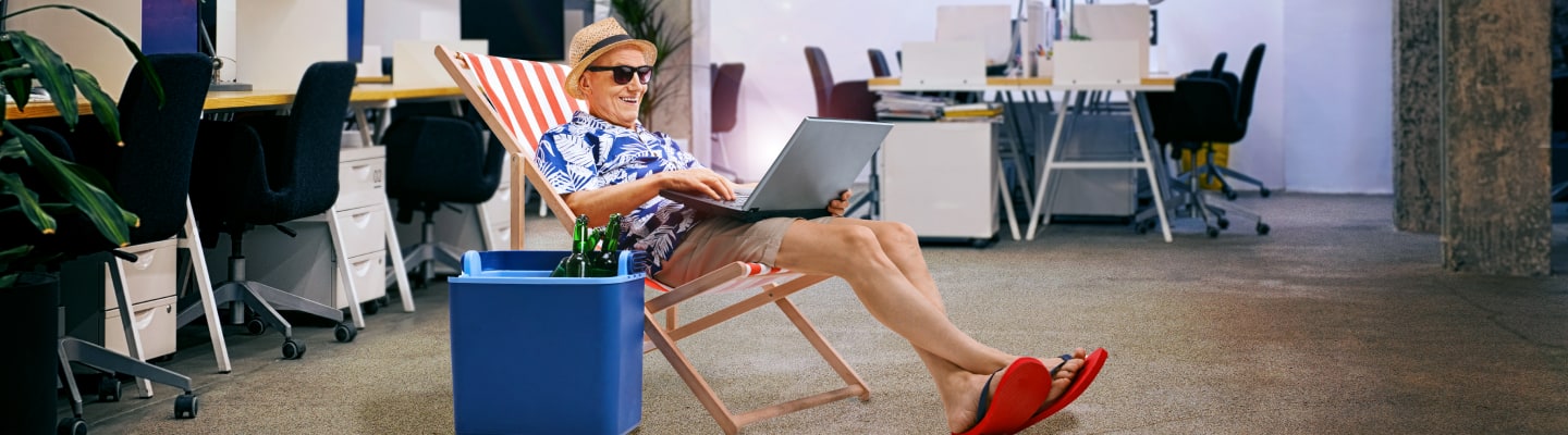 A man holiday ready sat in a deckchair on his laptop