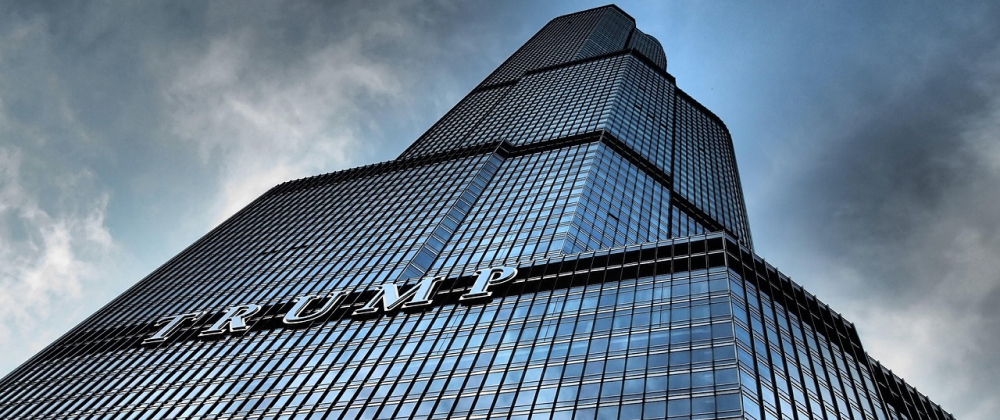 Glass skyscraper with TRUMP signage viewed from below against a dramatic cloudy sky — modern architecture in downtown Chicago.