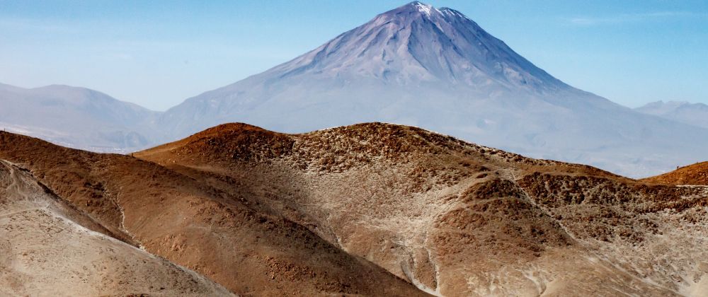 View of the volcanic landscape surrounding Kuélap in northern Peru with a snow-capped mountain in the distance.