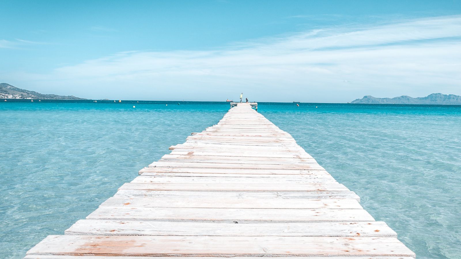 Wooden jetty stretching into the clear turquoise sea in Majorca, Spain.