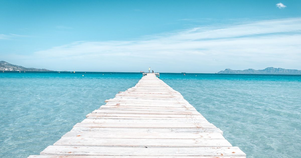 Wooden jetty stretching into the clear turquoise sea in Majorca, Spain.