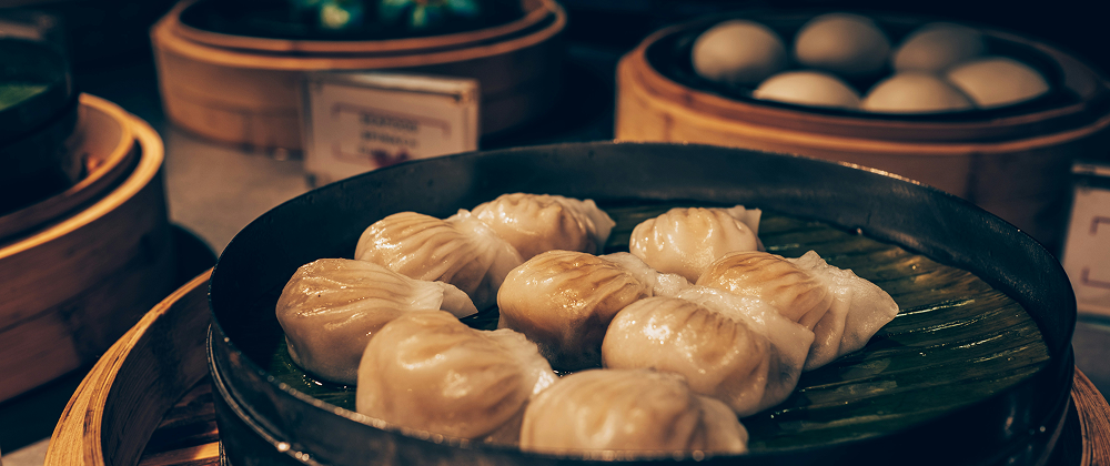 Steamed dumplings in a bamboo basket served on a banana leaf at a dim sum restaurant — traditional Chinese cuisine in a cozy setting.