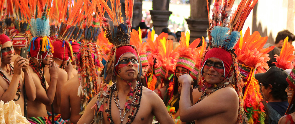 Group of men in colorful feathered headdresses and face paint celebrating at a traditional Indigenous festival — vibrant cultural expression.
