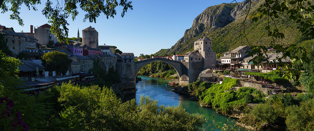 Snow-capped peaks of Torres del Paine rising above a turquoise lake in Patagonia, Chile — dramatic mountain landscape under a bright blue sky.