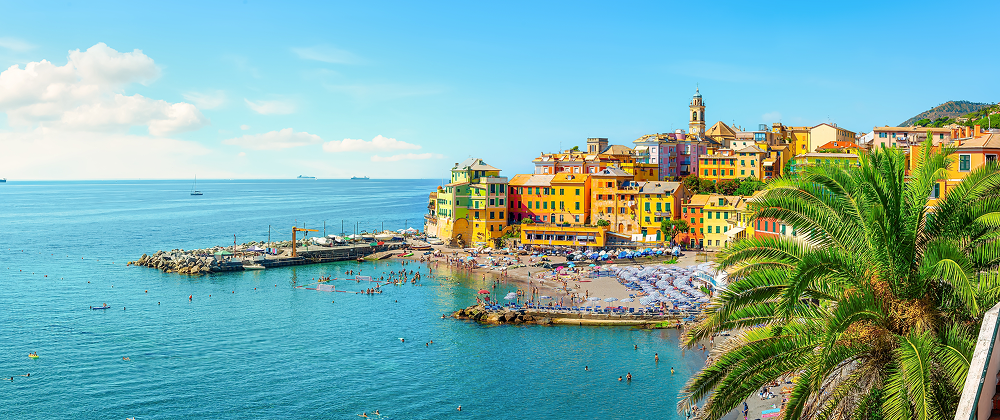 Colorful seaside town of Camogli, Italy with beachgoers, umbrellas, and clear blue waters — charming Mediterranean coastal village.