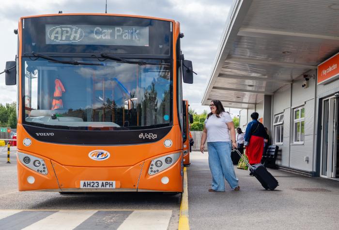 Woman boarding an APH Park & Ride shuttle bus to Gatwick Airport on a bright sunny day