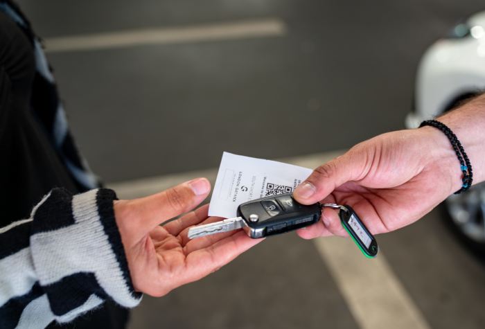 Close-up of hands exchanging car keys and a parking ticket for Airparks Meet & Greet at Gatwick Airport