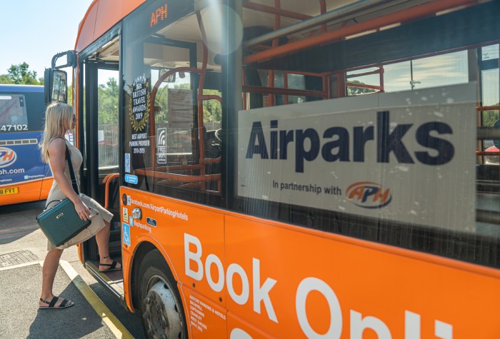 Woman boarding an Airparks Park & Ride shuttle bus to Gatwick Airport on a bright sunny day