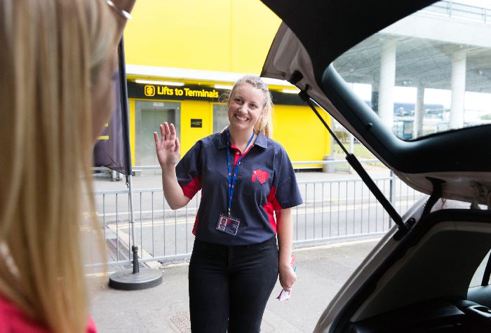Female passenger with an open car boot taking out luggage and being greeted by a friendly female I Love Meet & Greet driver at Gatwick Airport