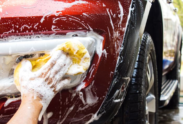 Close-up of a red car being washed by a staff member at I Love Valet Parking Gatwick Airport