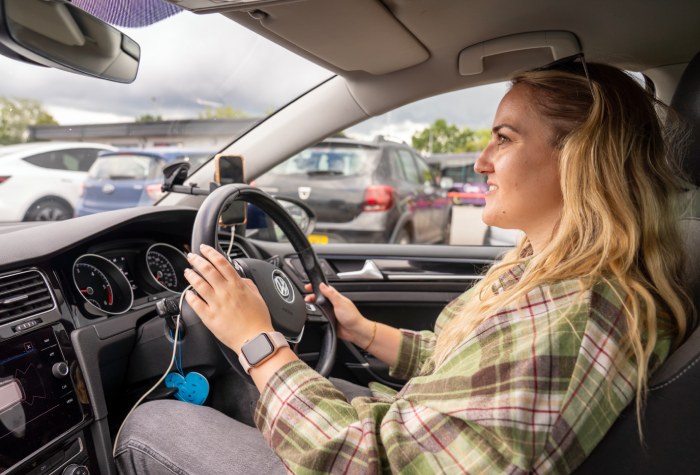 Smiling woman driving her car to park at the Holiday Extras Park & Ride at Gatwick Airport, photo taken from inside the car