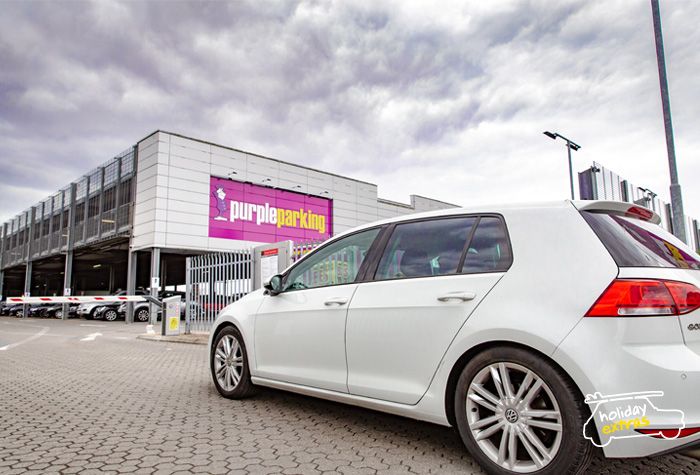 Customer driving a silver car into Heathrow Purple Parking Park and Ride, with the Purple Parking sign in view