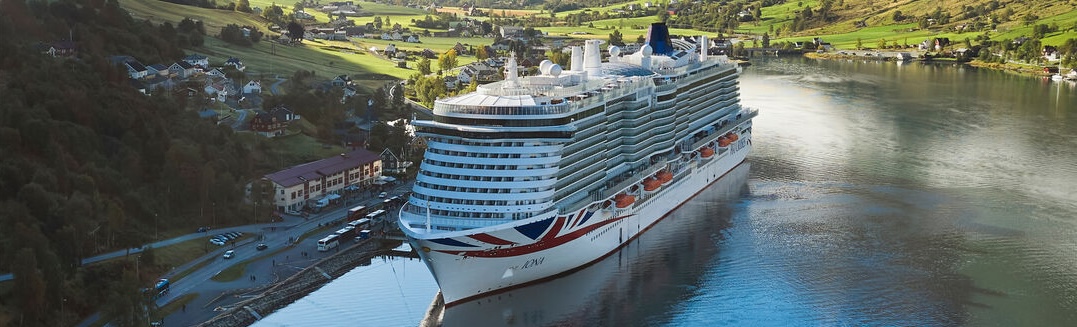 An aerial view of a cruise ship with a large pool deck visible at the rear, and a spacious area with lounge chairs and sunbeds.