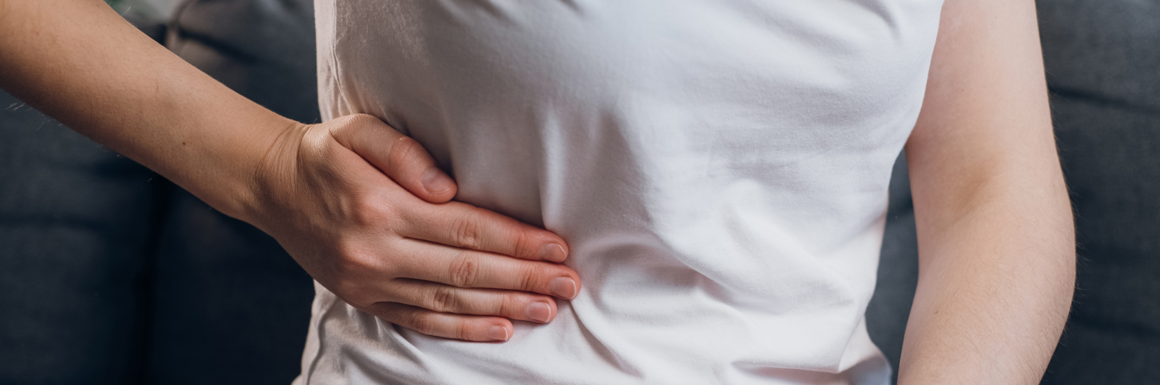 A person clutching their side in discomfort, representing abdominal pain caused by gallstones – a common concern when travelling with gallstones.
