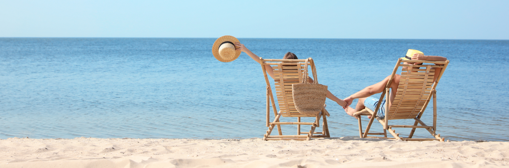 two people sitting on the beach in their deck chairs
