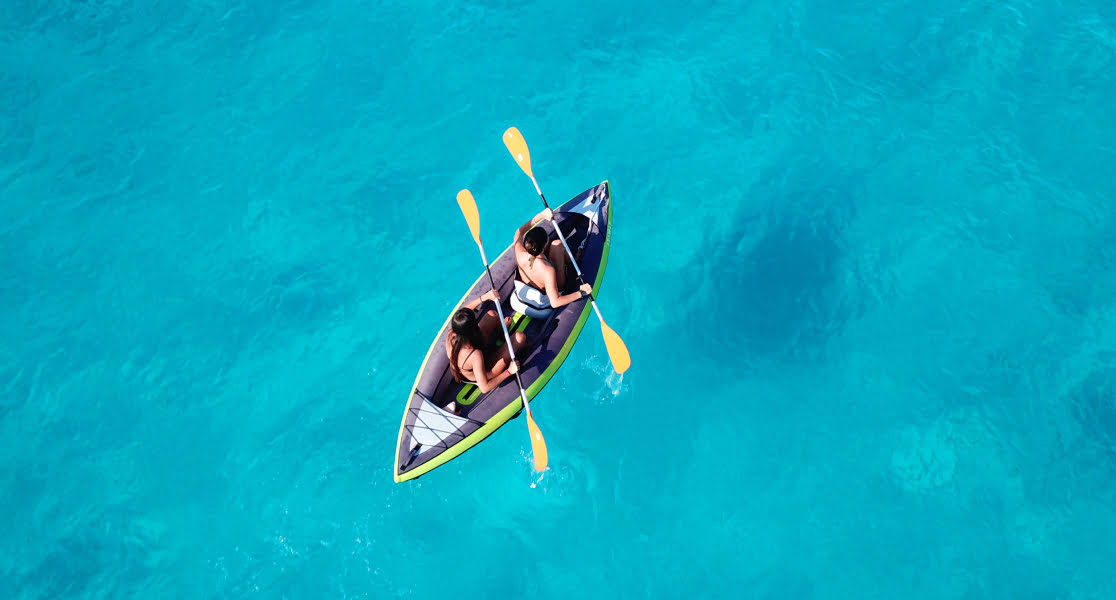 Two women kayaking in crystal blue waters
