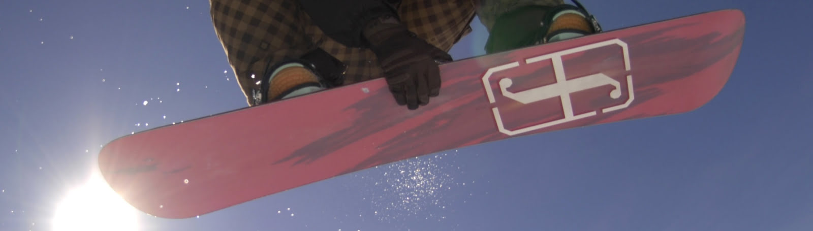 Person gripping a red snowboard performing a jump