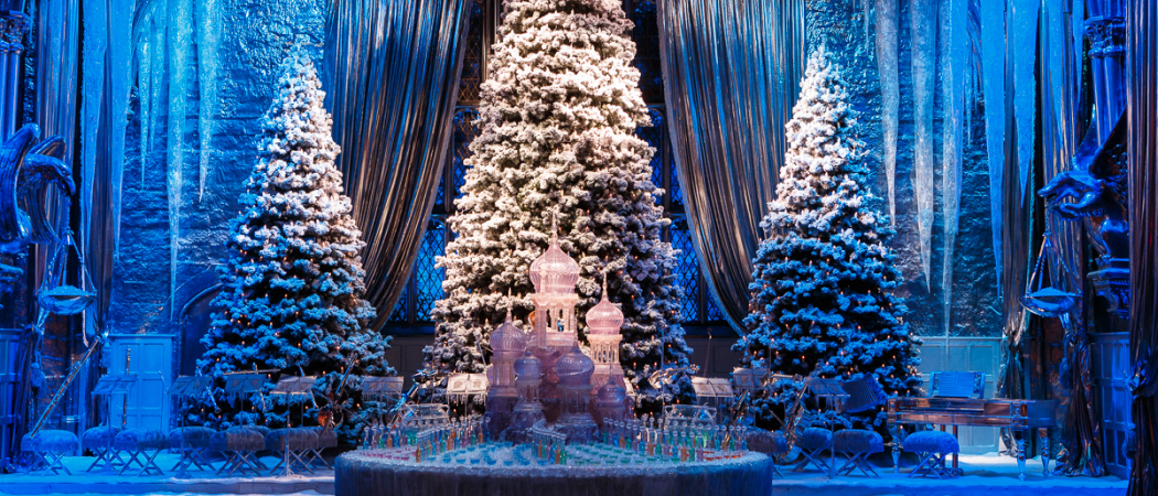 A festive, snow-covered scene inside the Hogwarts Great Hall, decorated for Christmas.