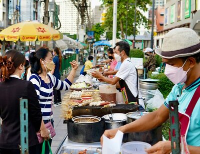 Verschieden Streetfood Stände in Thailand mit Personen, die Essen kaufen