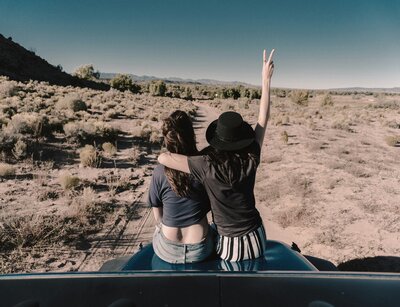 Zwei Frauen sitzen auf der Motorhaube am Strand