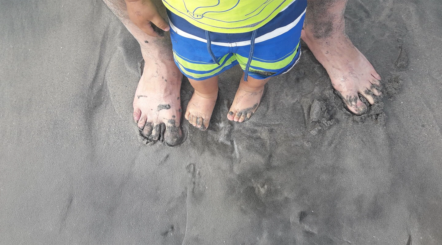 Männer- und Kinderfüße im Sand