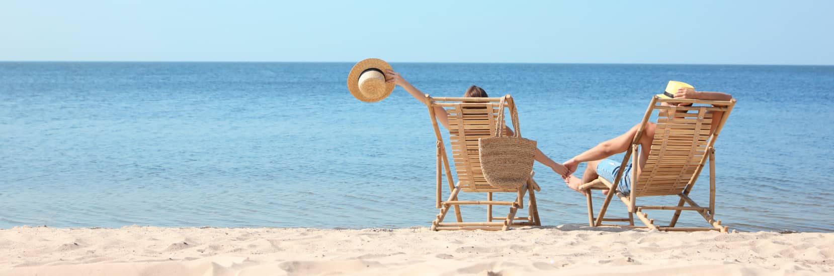 couple on the beach sat on sun lounges